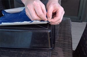 two hands cut into a hoof pad made of strips of tape